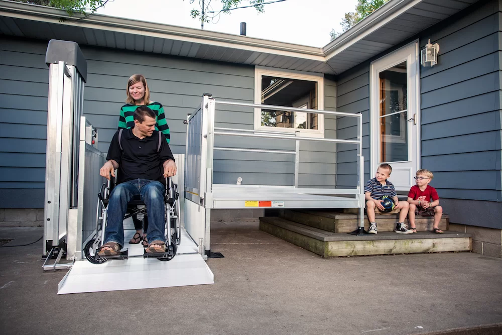 A man using an electric lift to get up onto his entryway.